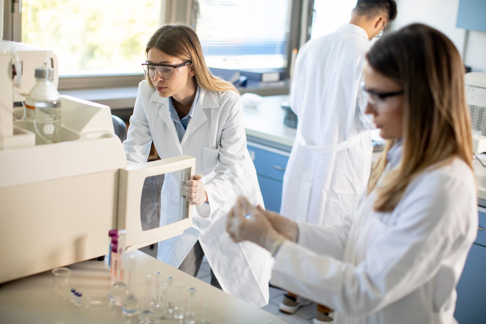 Female scientists in a white lab coat putting vial with a sample